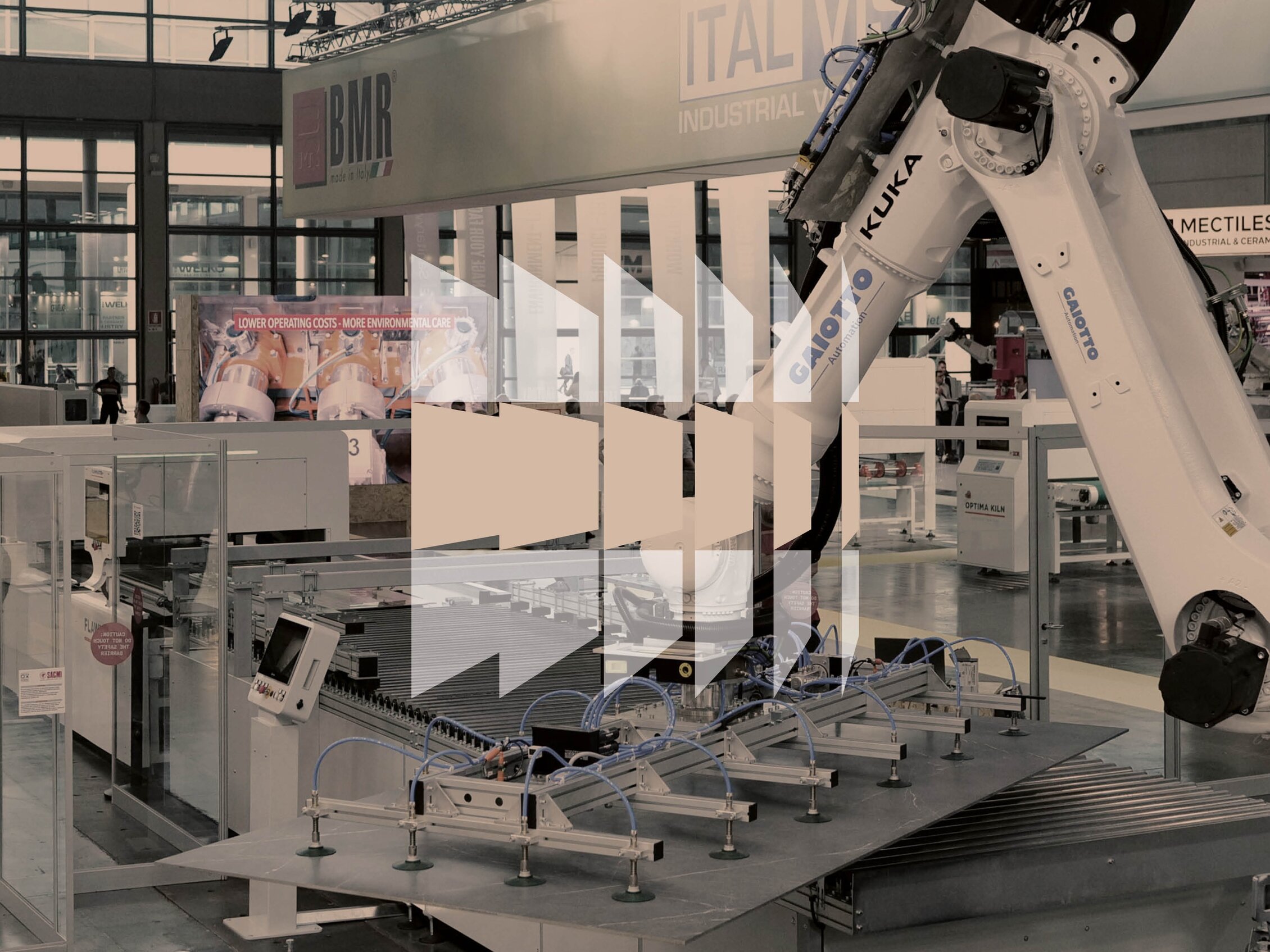 Braccio robotico industriale in funzione all’interno di una fiera tecnologica, con macchinari avanzati e sistemi automatizzati esposti.