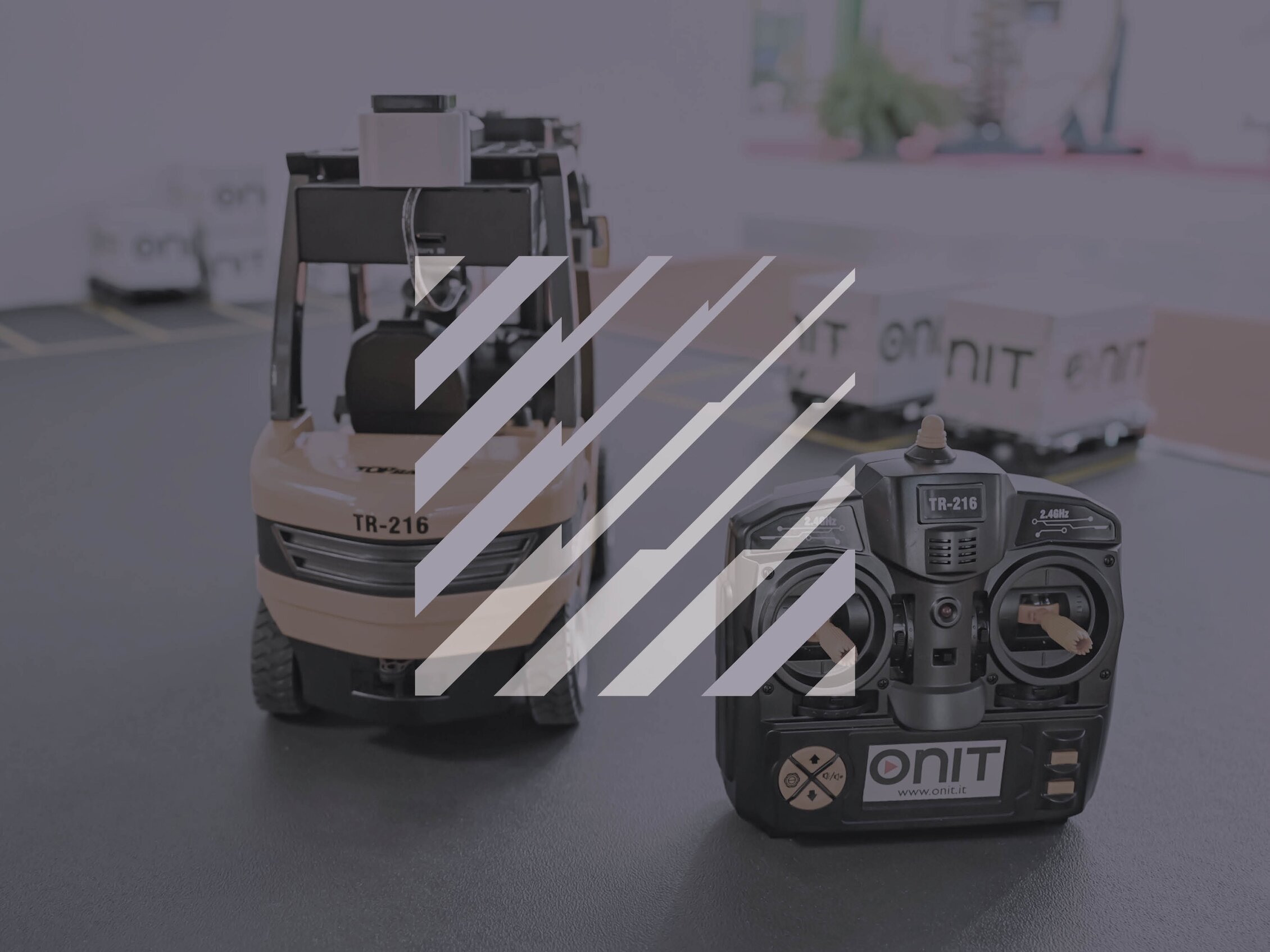 Modellino di carrello elevatore con radiocomando utilizzato per una dimostrazione tecnologica in fiera, dedicata a logistica e automazione industriale.