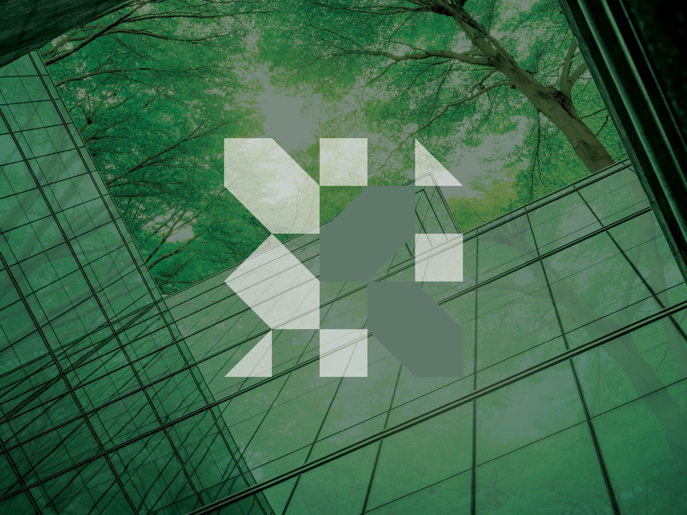 Facciata di un edificio moderno in vetro che riflette una foresta verde. Al centro, un elemento grafico geometrico della fiera.