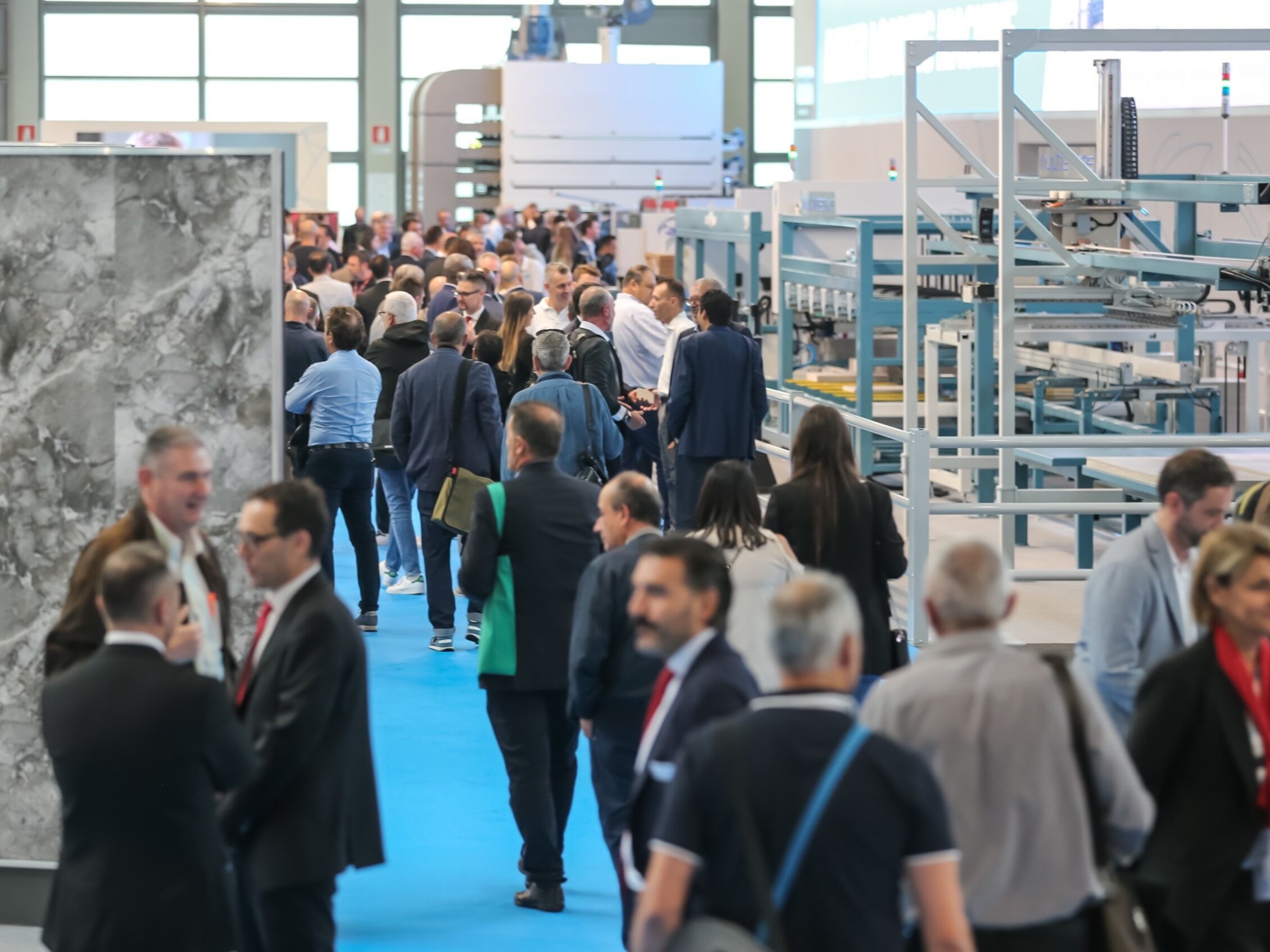 Folla di professionisti che visita gli stand e i macchinari esposti durante una fiera industriale.