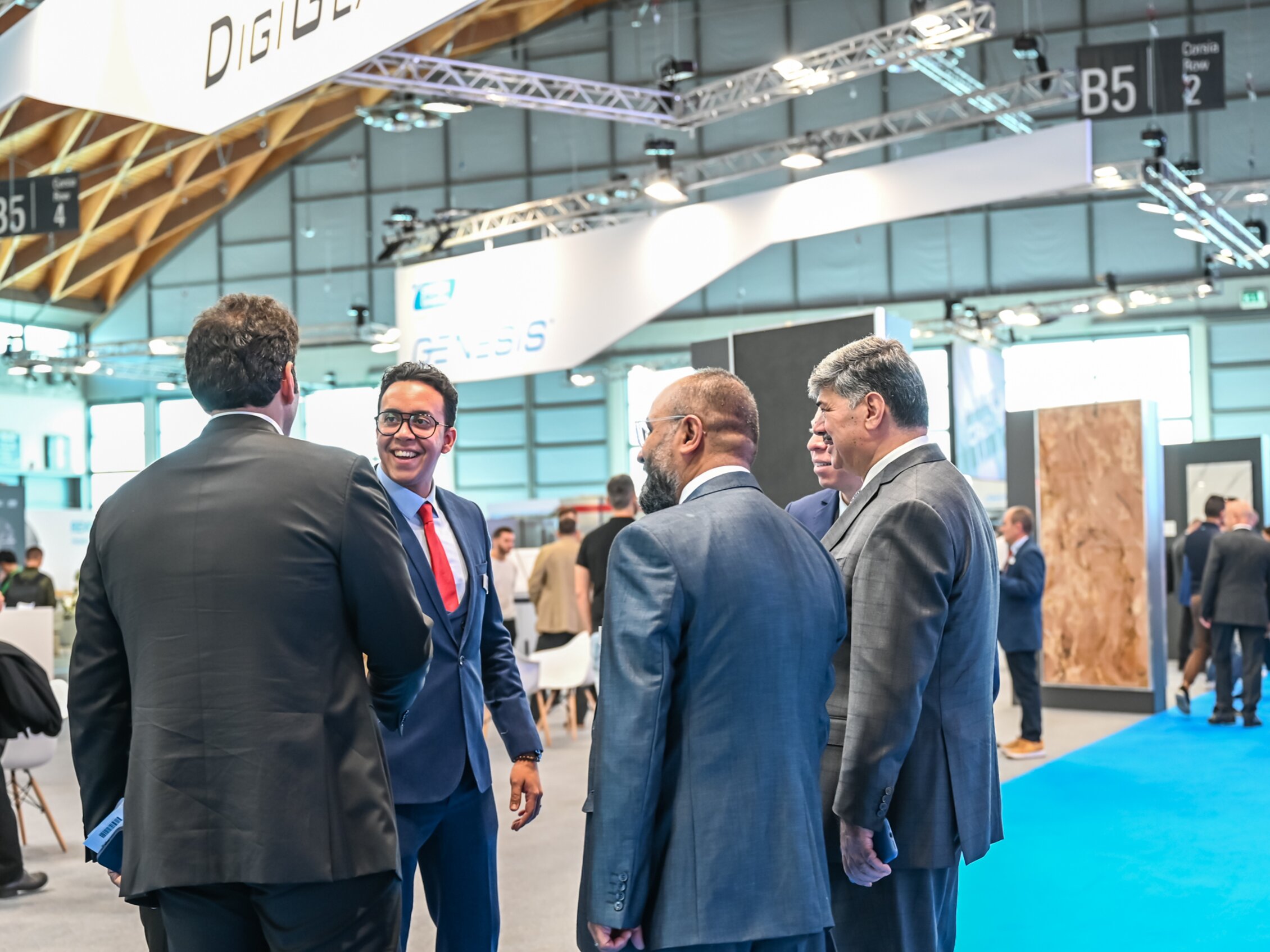 Professionisti in abiti formali che conversano e fanno networking negli spazi espositivi.