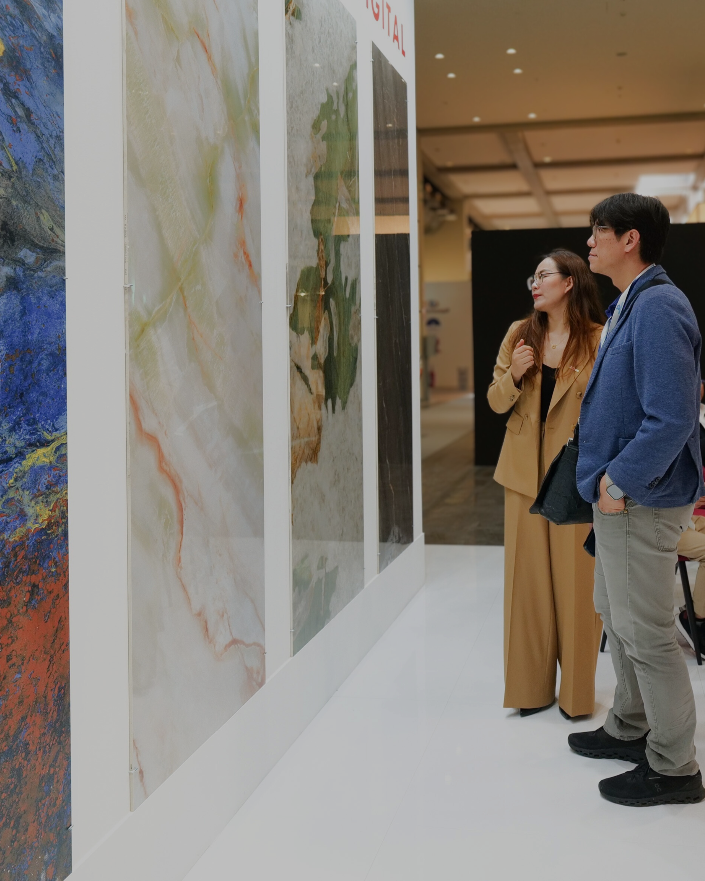 Due persone osservano da vicino grandi pannelli decorativi esposti a TECNA.