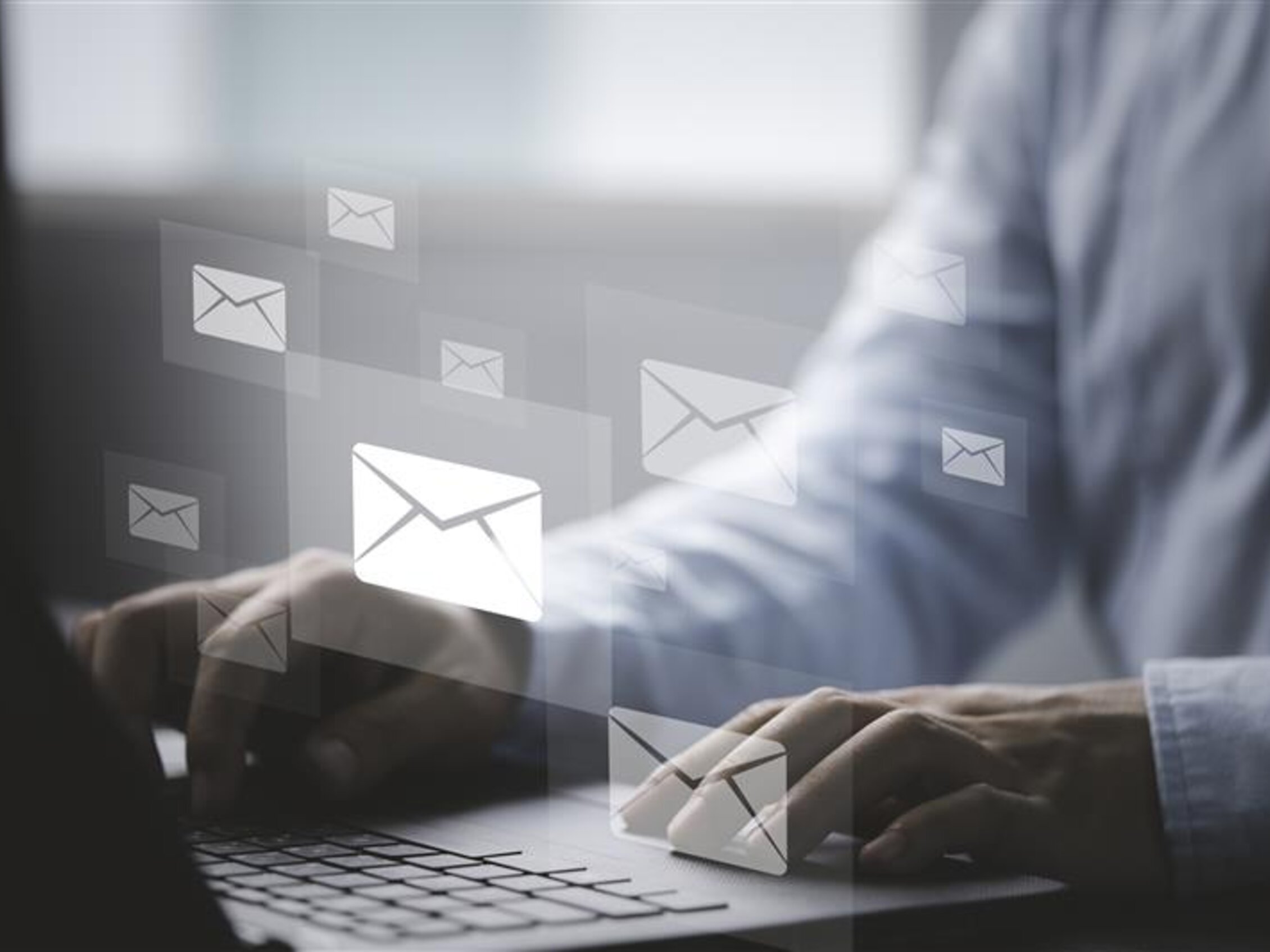 Professionista che digita su un laptop, con icone di email digitali sovrapposte